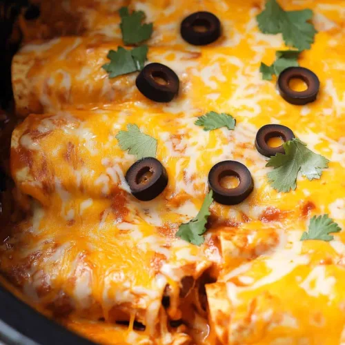 Homemade Mexican-style chicken casserole with melted cheddar cheese and enchilada sauce in a crock pot