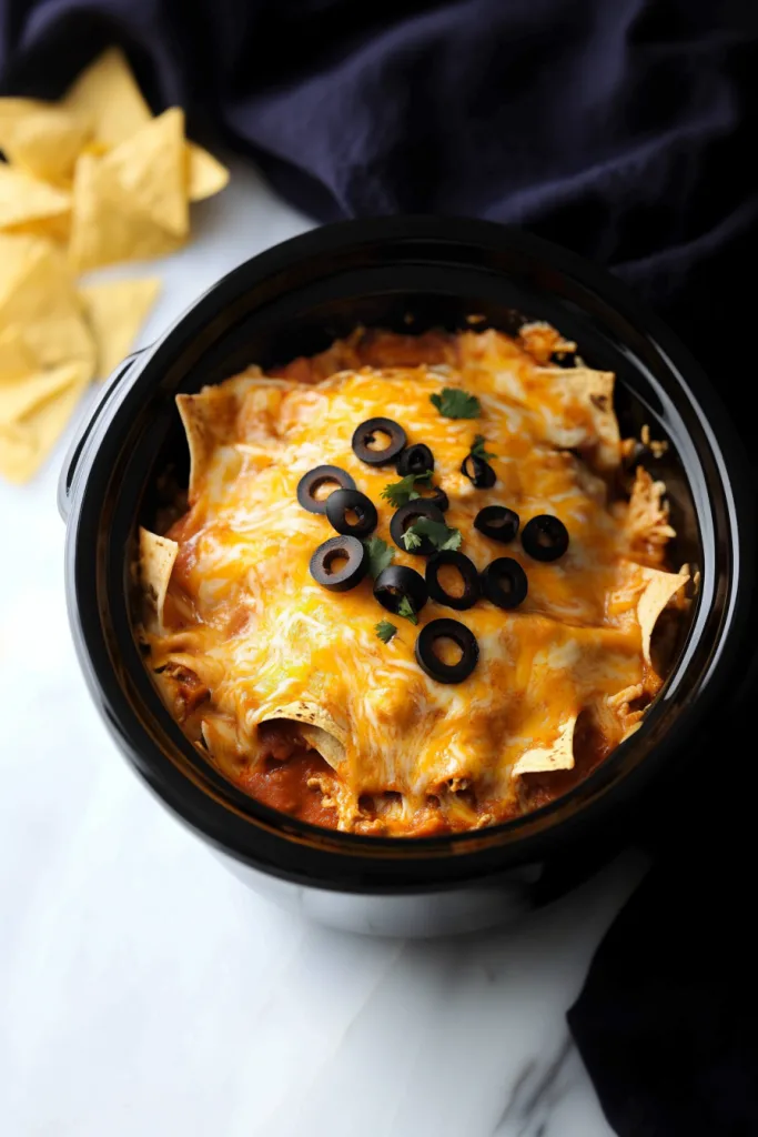 Cheesy enchilada casserole served hot from the crock pot with layers of chicken, tortillas, and enchilada sauce