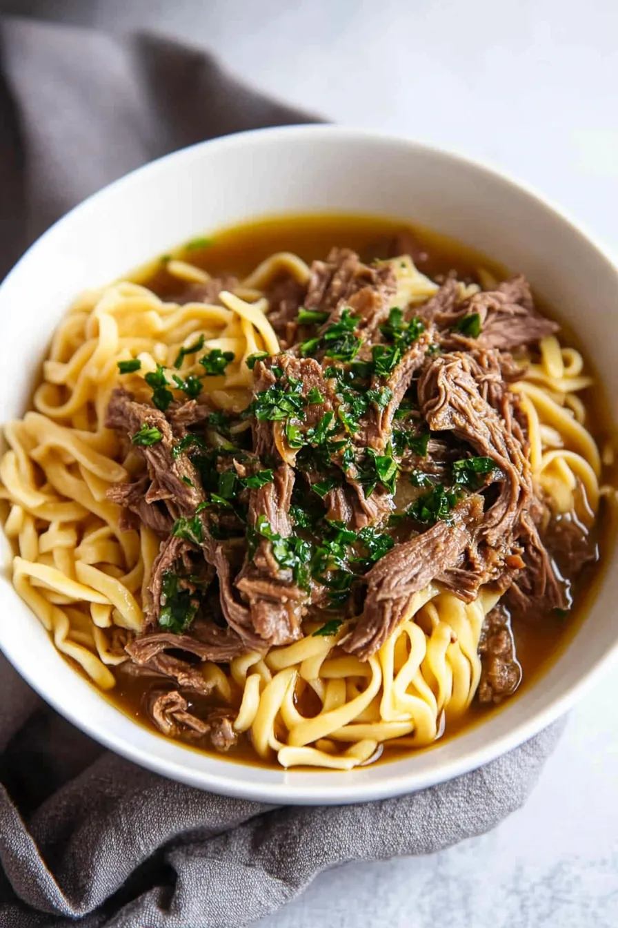 Hearty beef and noodles topped with fresh parsley and flavorful slow-cooked juices
