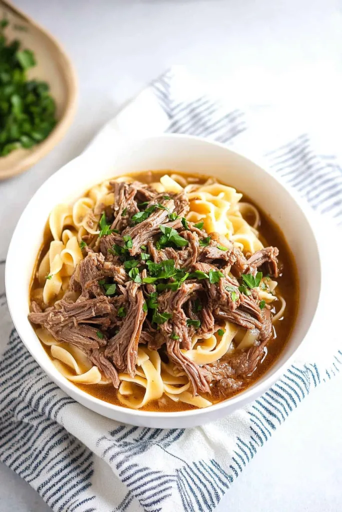 Warm bowl of shredded beef with egg noodles and savory broth for an easy family meal