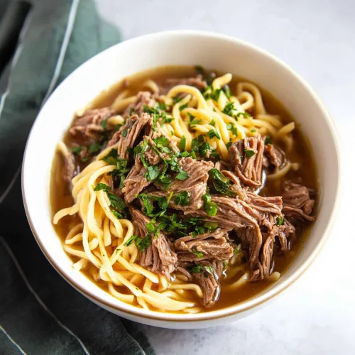 Comfort food dinner with slow-cooked beef, savory gravy, and soft noodles in a bowl
