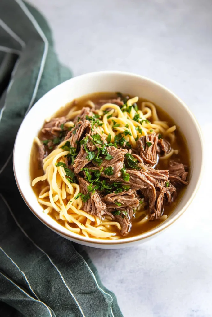 Comfort food dinner with slow-cooked beef, savory gravy, and soft noodles in a bowl