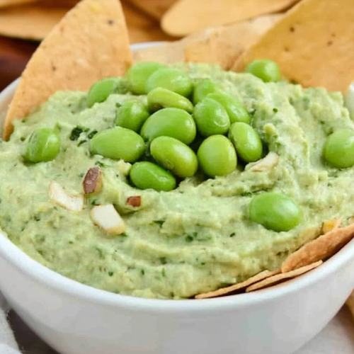 Creamy green dip topped with whole edamame beans and crunchy garnish.