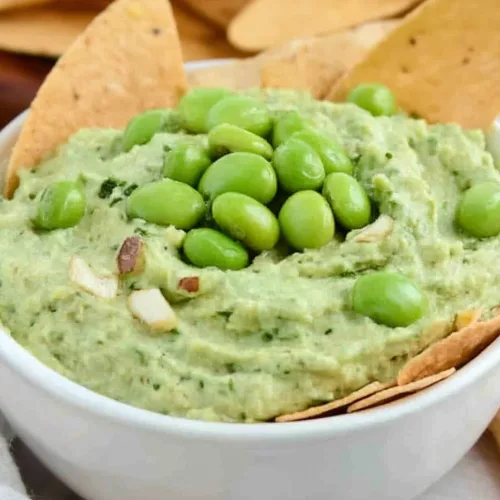 Creamy green dip topped with whole edamame beans and crunchy garnish.