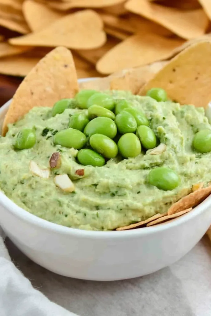 Creamy green dip topped with whole edamame beans and crunchy garnish.