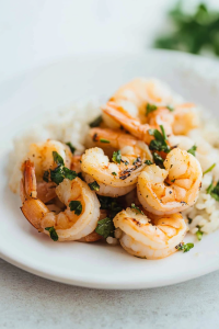 Final dish presentation: shrimp with a light char, paired with rice and fresh cilantro leaves.
