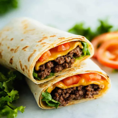 Freshly made beef and cheese tortilla wraps served with lettuce and sliced tomatoes on the side.