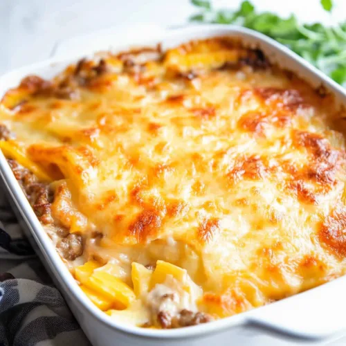 Freshly baked casserole with rich cheesy crust and hints of parsley garnish in the background.