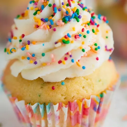 Festive dessert topped with rainbow sprinkles against a softly blurred background.