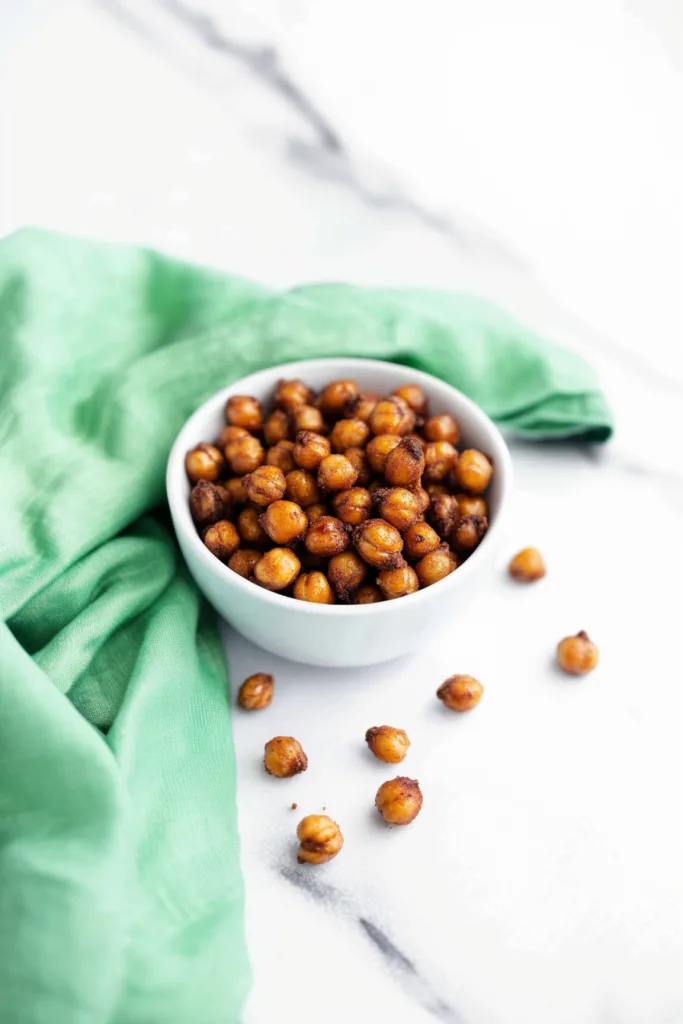 White bowl filled with roasted chickpeas coated in glossy seasoning.
