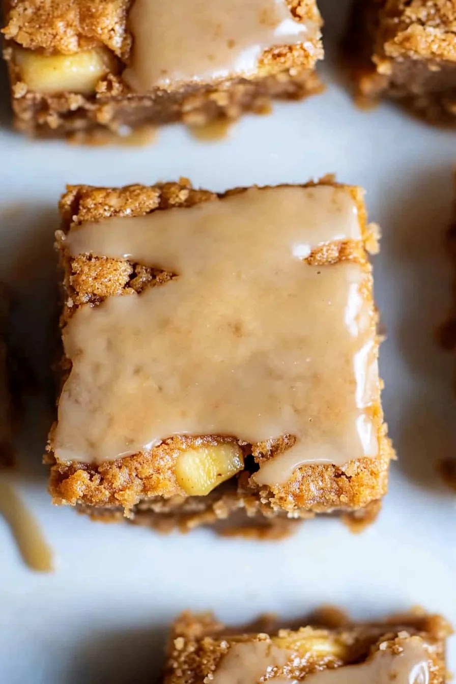 Overhead view of several glazed blondies arranged neatly, their spiced aroma suggested by the golden hue.