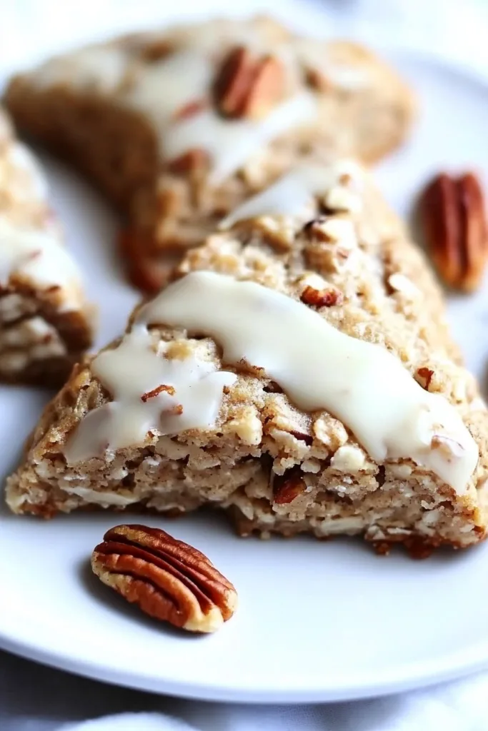 Golden brown breakfast scones with oats, chopped pecans, and a smooth maple icing drizzle