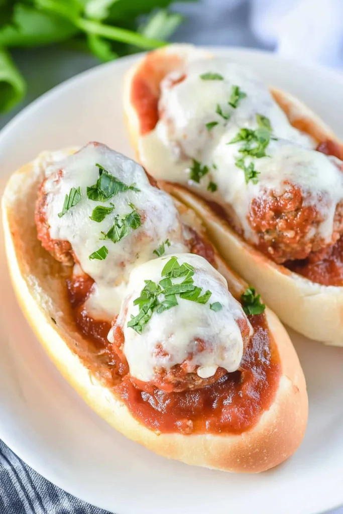 White plate holding a sub sandwich with rich red sauce and creamy mozzarella.