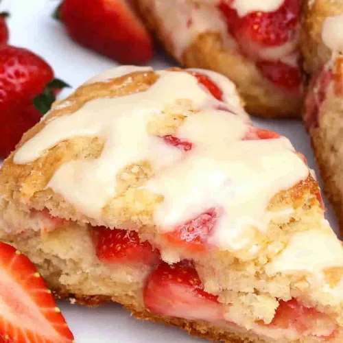 Rustic presentation of strawberry scones with shiny glaze and fruit garnish.
