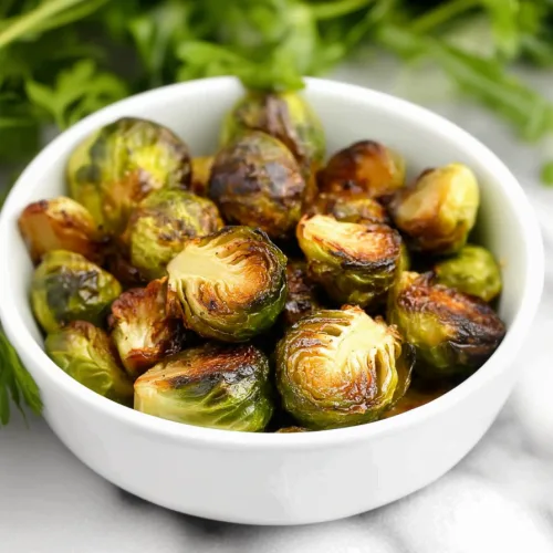 Bowl of crispy Brussels sprouts sprinkled with garlic and fresh rosemary.