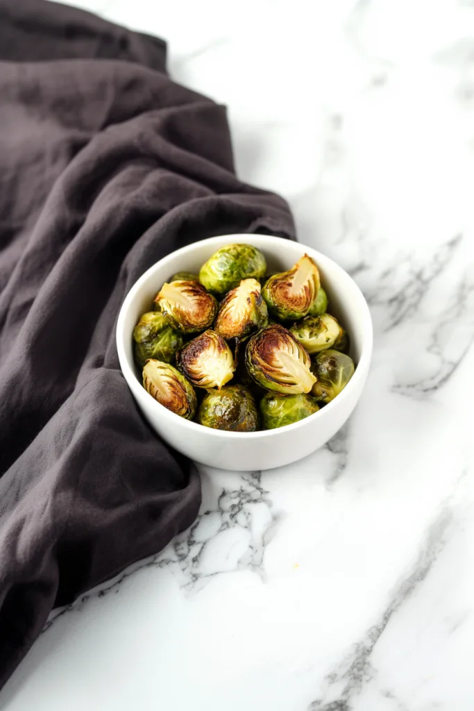 Healthy side dish of oven-roasted sprouts with browned surfaces and herbs.
