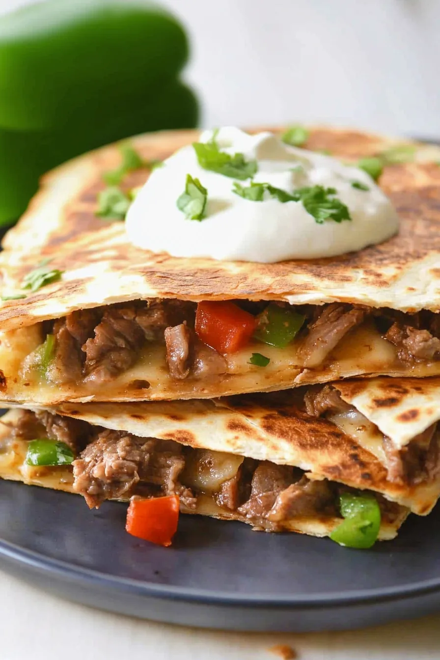 Sliced quesadilla triangles arranged on a dark plate with sour cream garnish.