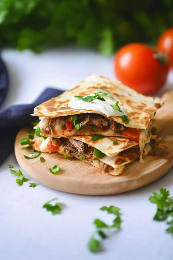 Final serving shot showing quesadilla halves topped with fresh cilantro and a dollop of cream.