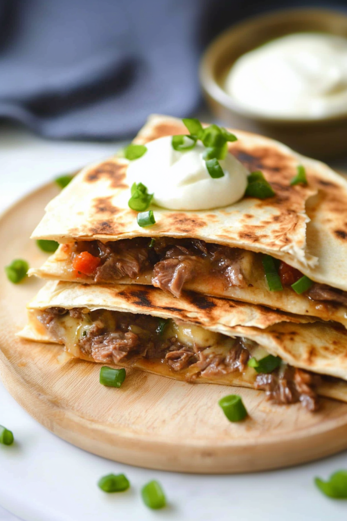 Golden quesadilla wedges stacked neatly with melted cheese and steak peeking through the layers.