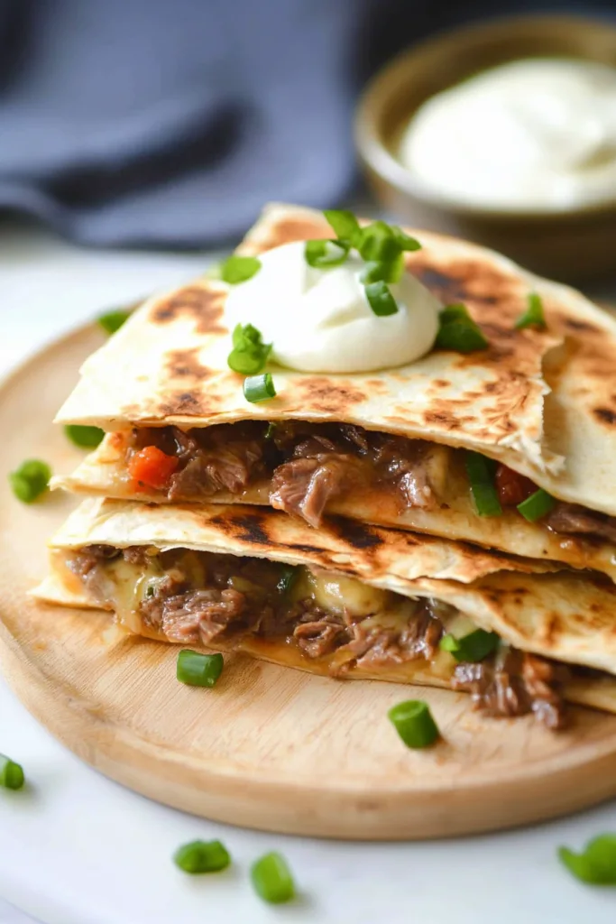 Golden quesadilla wedges stacked neatly with melted cheese and steak peeking through the layers.