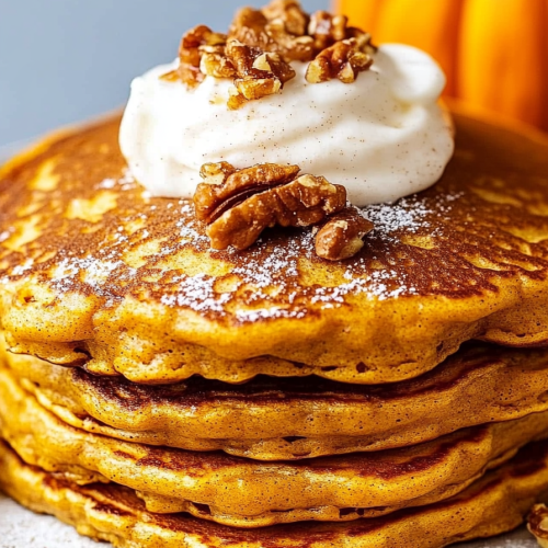Seasonal breakfast plate featuring warm pancakes beside a small pumpkin.