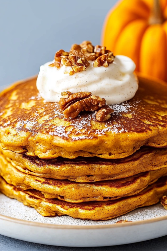 Seasonal breakfast plate featuring warm pancakes beside a small pumpkin.