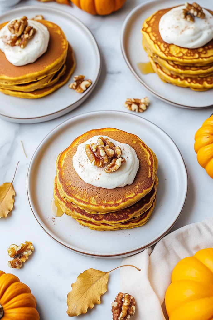 Overhead view of pancakes layered high with creamy topping and autumn garnish.