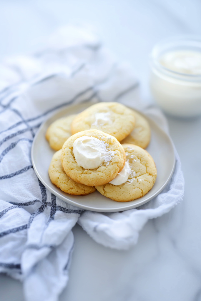 Soft homemade cookies topped with creamy frosting and served on a white plate.