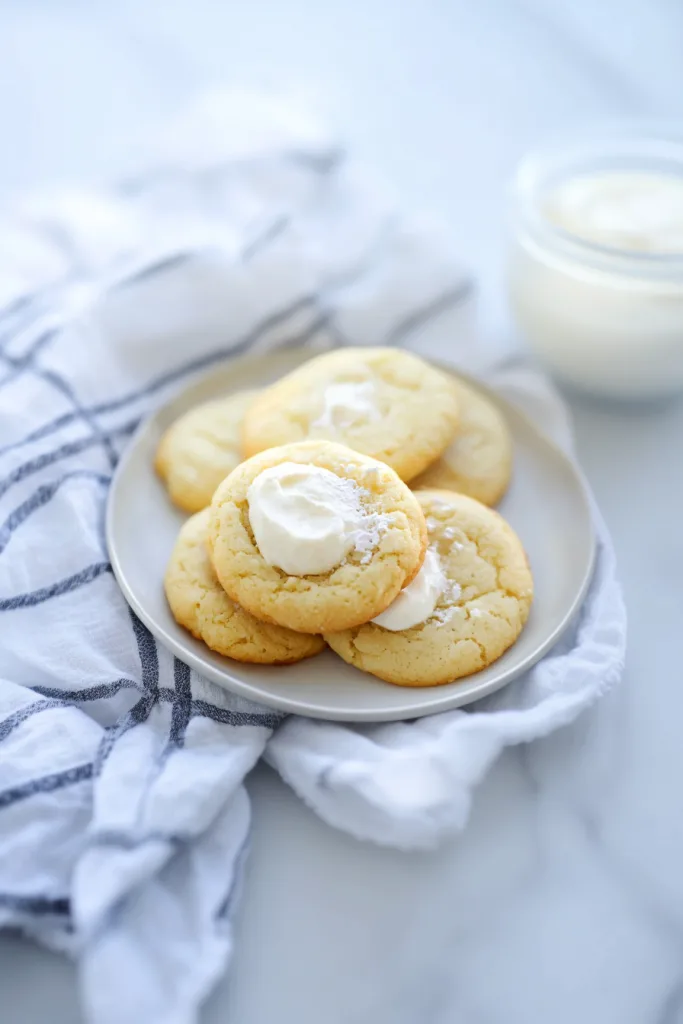 Soft homemade cookies topped with creamy frosting and served on a white plate.