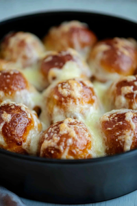 Homemade baked appetizer with fluffy bread bites and bubbling melted cheese in a skillet.