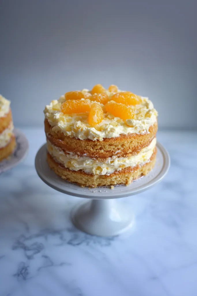 Soft frosted celebration cake dusted with powdered sugar and citrus segments