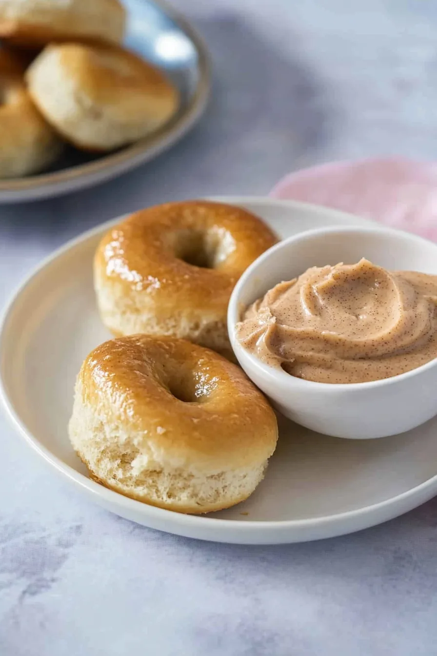 Freshly baked rolls arranged neatly with a light sheen, paired with cinnamon spread.