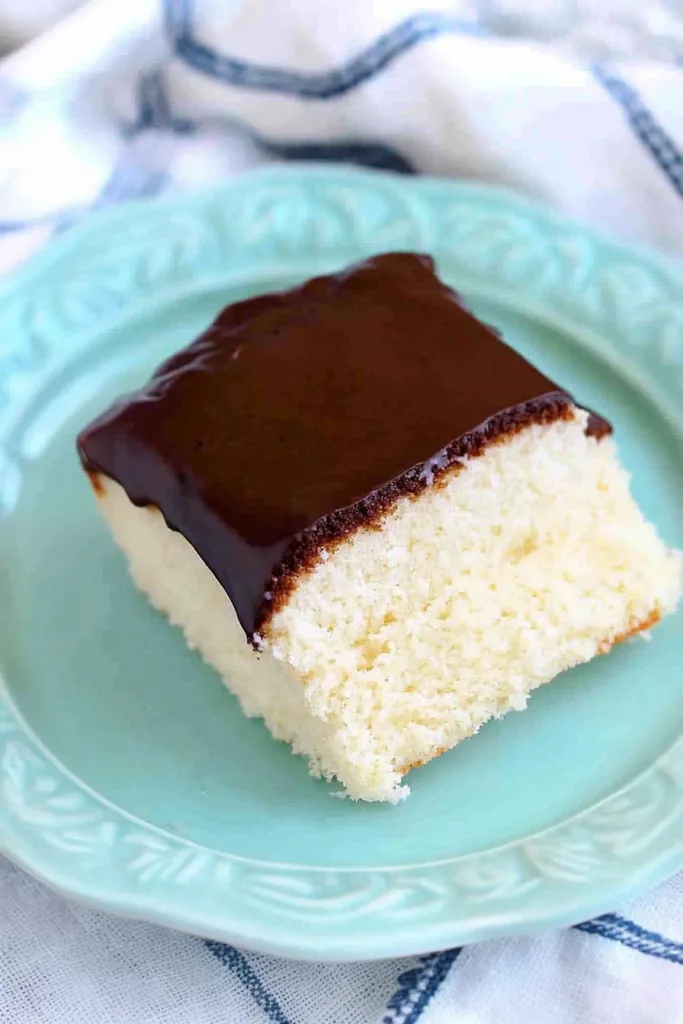 Overhead view of a baking pan filled with frosted cake, with slices served on plates nearby.
