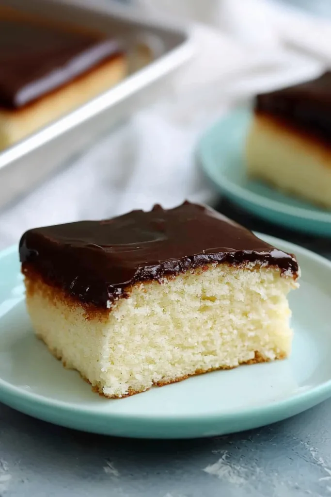 Rustic dessert presentation showing a thick frosted cake slice beside the whole pan.