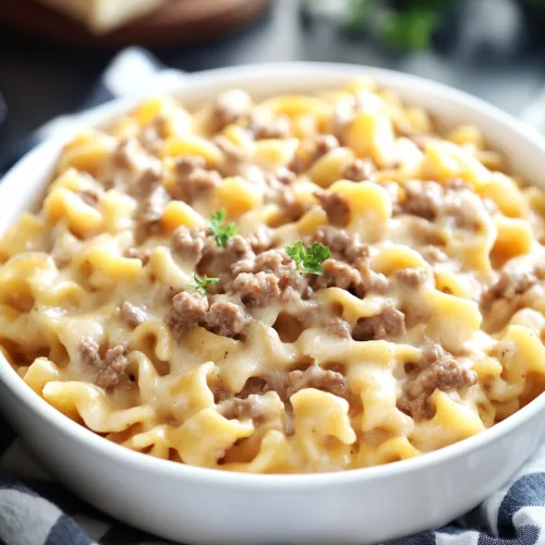Golden baked noodles with melted cheese and beef in a white casserole dish.