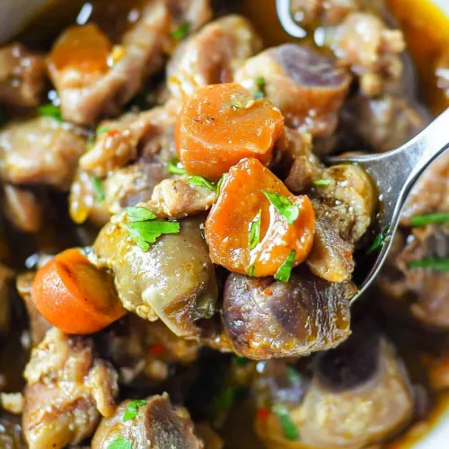 Close-up of hearty braised dish highlighting browned meat and herbs.
