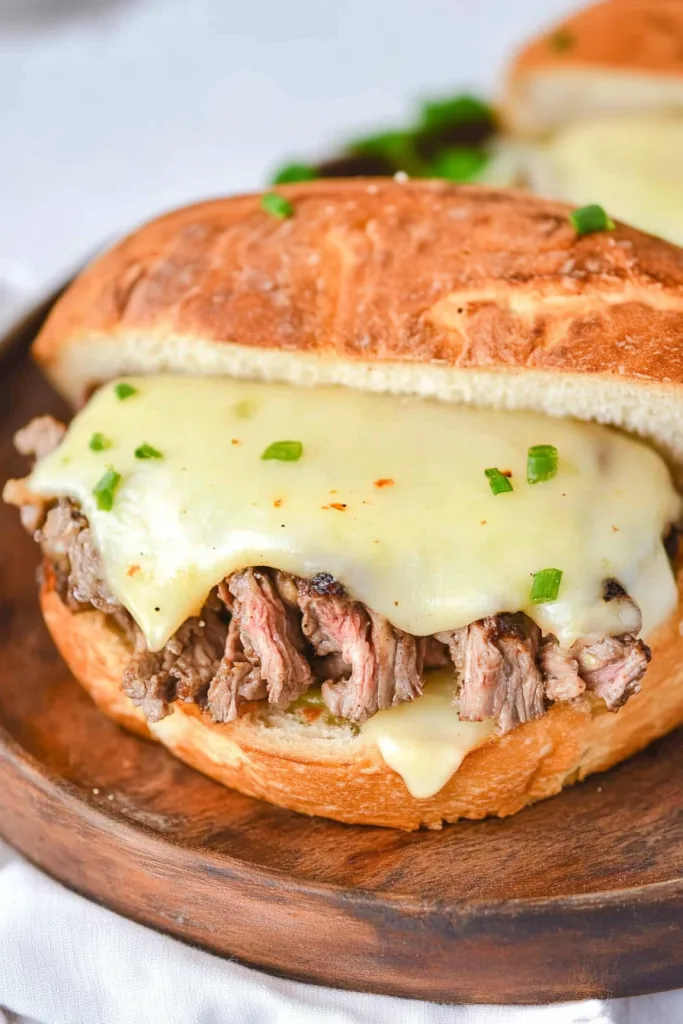 Toasted sandwich bun filled with shredded beef and topped with creamy melted cheese.