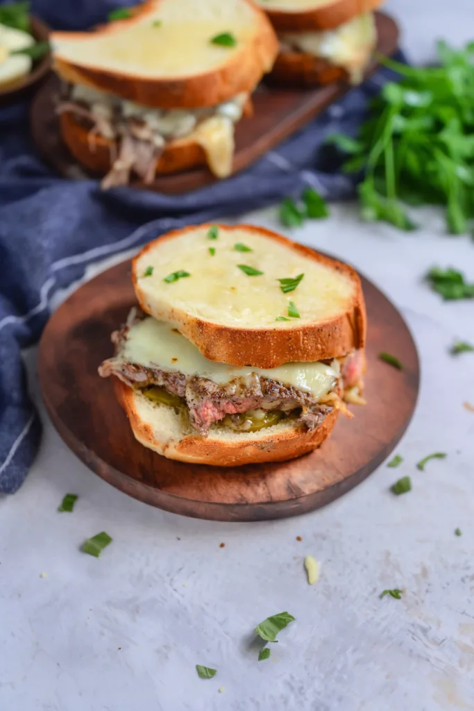 Hearty beef and cheese toast served on a rustic wooden plate.