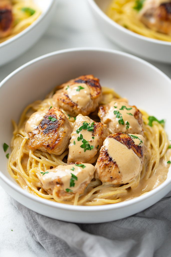 Hearty chicken and pasta dish served in a white bowl with creamy sauce.