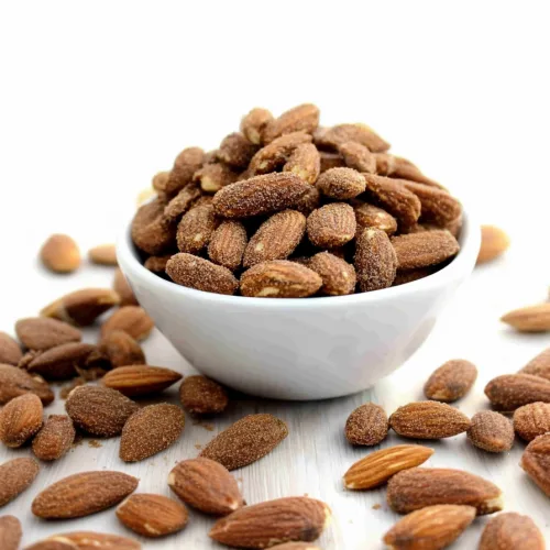 White bowl filled with roasted almonds coated in a fine seasoning.