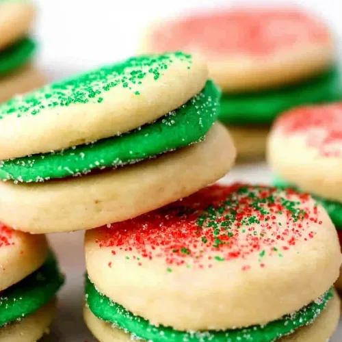 Close-up of sugar cookies layered with green filling and redโgreen sugar topping.