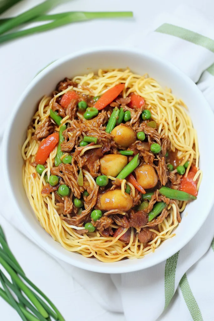 Bowl of glossy noodles with beef, carrots, and green beans