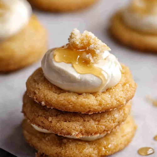 Stack of golden cookies layered with frosting and topped with a drizzle of syrup.