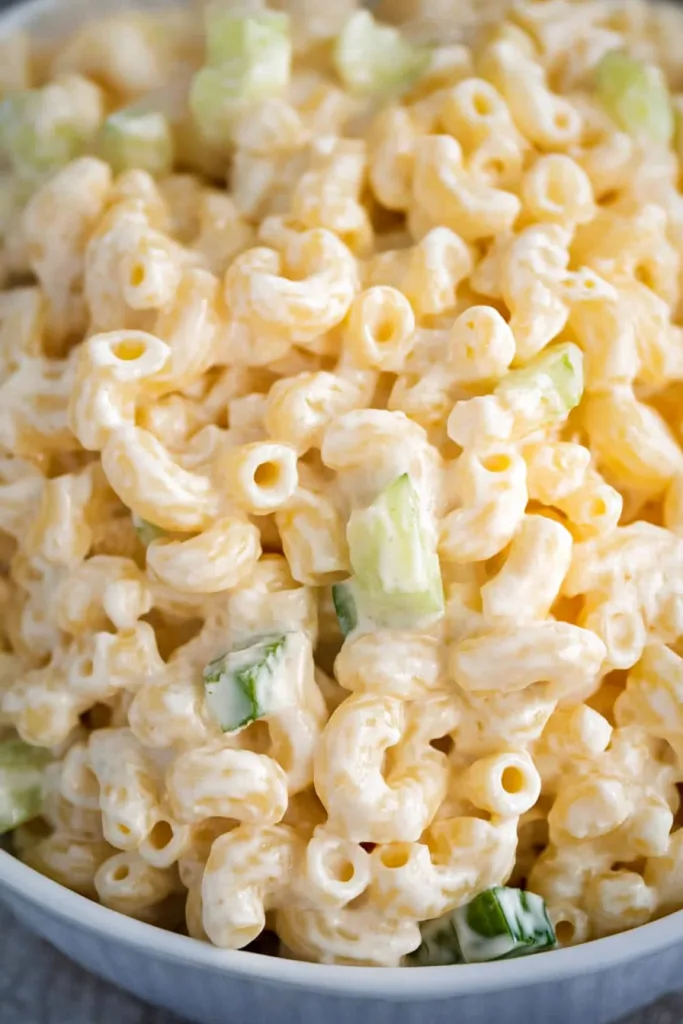 Overhead view of the finished mac salad, showing pasta and vegetables evenly coated in creamy sauce.