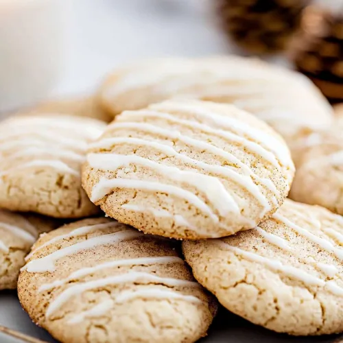 Plate of freshly baked cookies, warm golden color with festive pinecones blurred in the background.