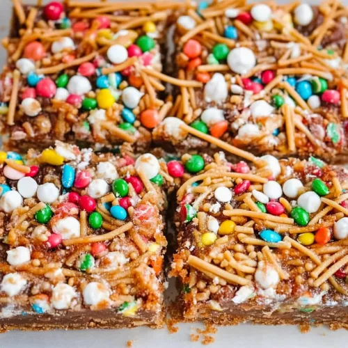 Closeโup of cookie bars topped with vibrant chocolate candies and drizzle.