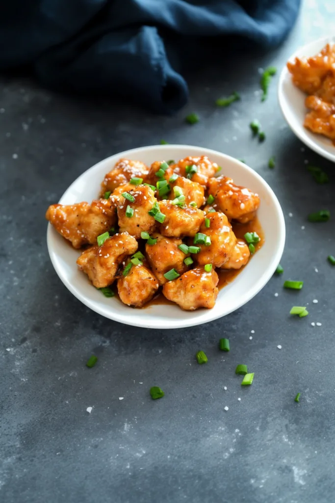 Homemade spicy chicken appetizer with sticky sauce, sesame seeds, and chopped scallions