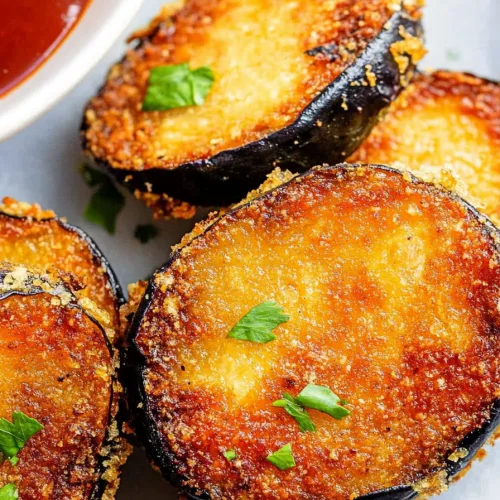Stacked slices of fried eggplant highlighting golden crust.