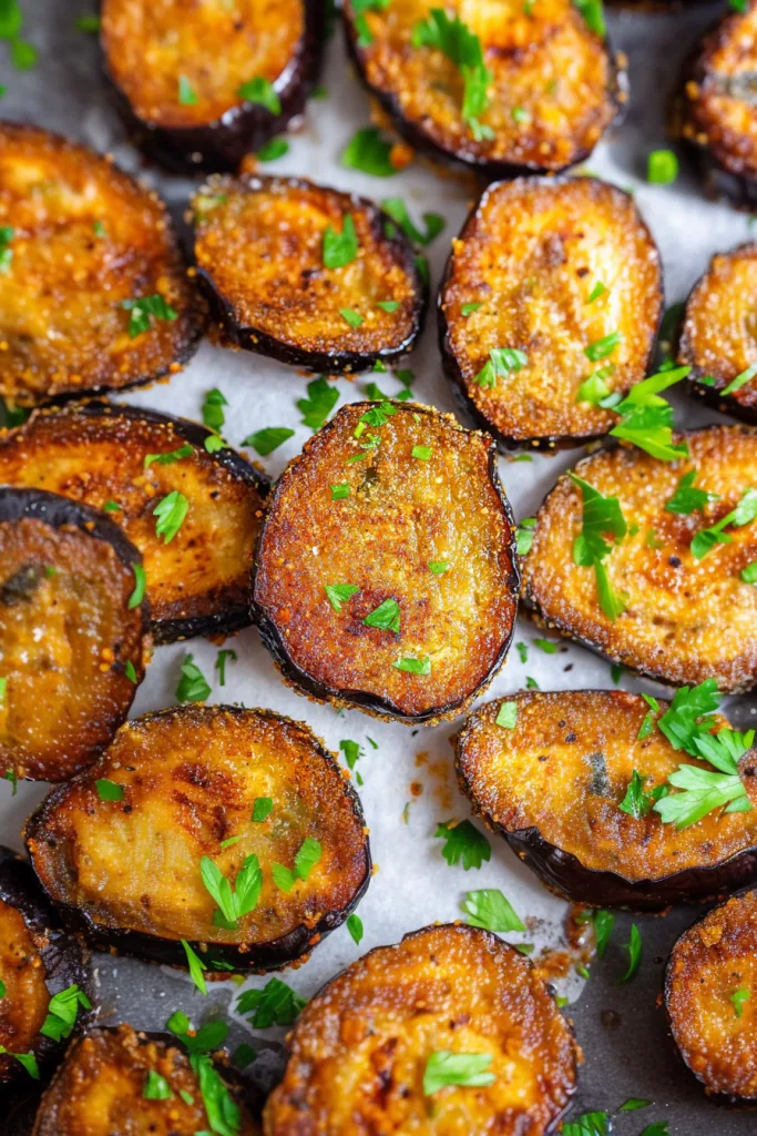 Golden-brown eggplant slices with crispy coating and herb garnish.