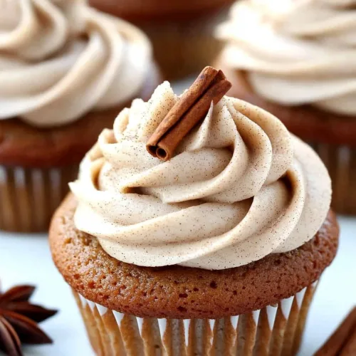 Arrangement of frosted cupcakes with decorative cinnamon sticks and star anise.